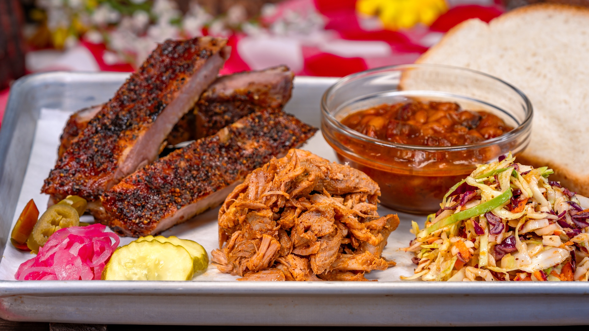 Disney Parks America 250 Foodie Guide Smoked Barbecue Combo Platter: a selection of house-smoked meats, with baked beans, coleslaw, white bread, and pickled vegetables. Select two: pork spareribs, pulled pork, sausage link, or beef brisket