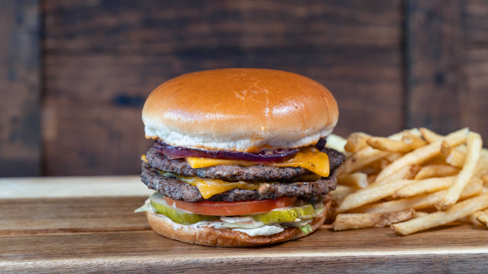 Disney Parks America 250 Foodie Guide Double Cheeseburger: Two angus beef patties, cheddar, lettuce, tomato, pickles, grilled onion, and SJG burger sauce served with fries