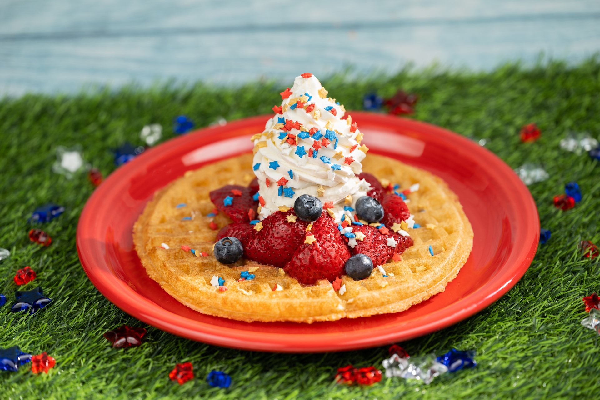 Disney Parks America 250 Foodie Guide Red, White, and Blue Waffle: Waffle topped with mixed berries, vanilla ice cream, whipped cream, and festive sprinkles