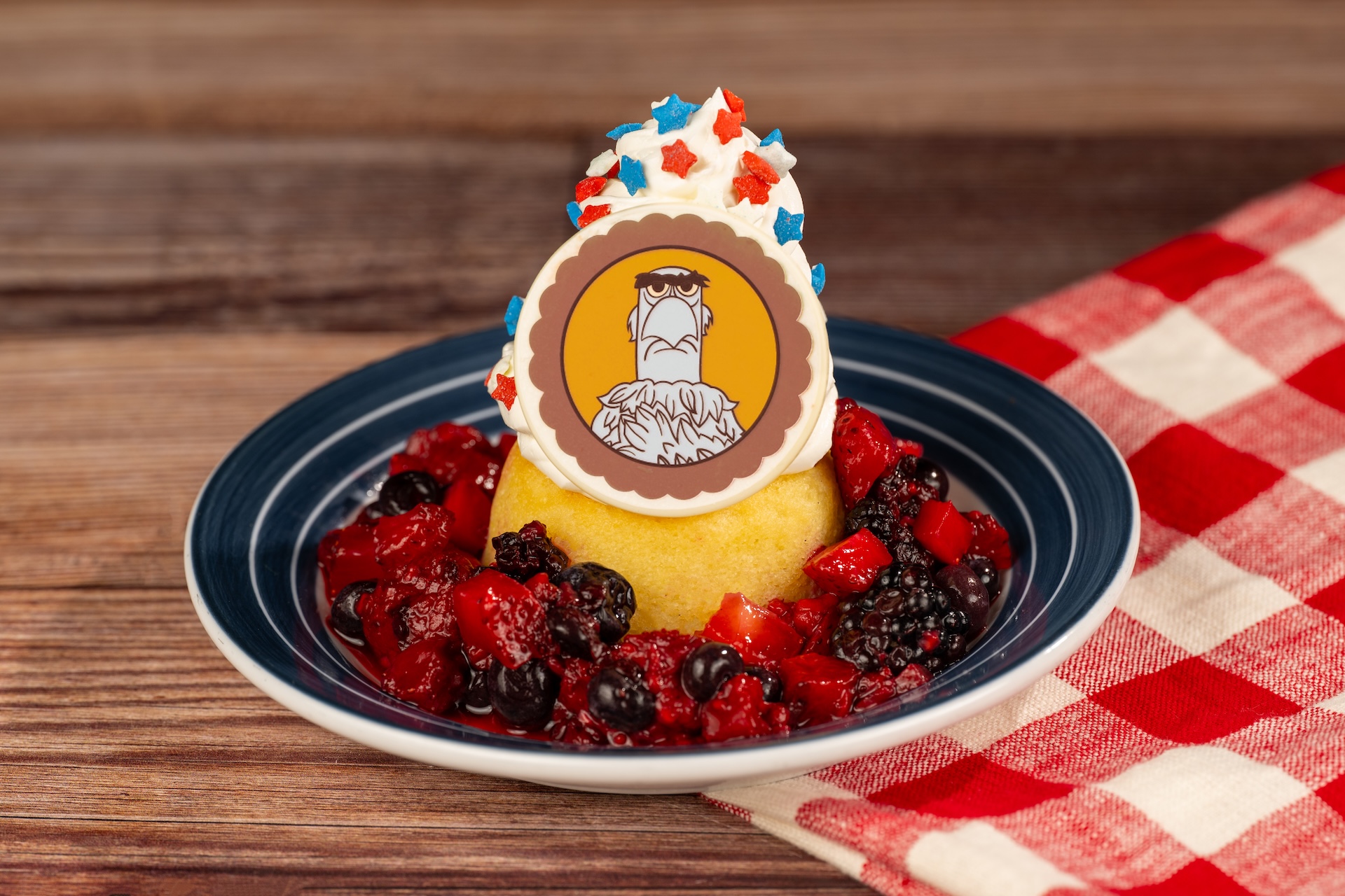 Disney Parks America 250 Foodie Guide Sam Eagle Star-Spangled Shortcake: Vanilla cake with strawberries, blackberries, blueberries, whipped cream, star sprinkles, and a Sam Eagle chocolate coin (New)