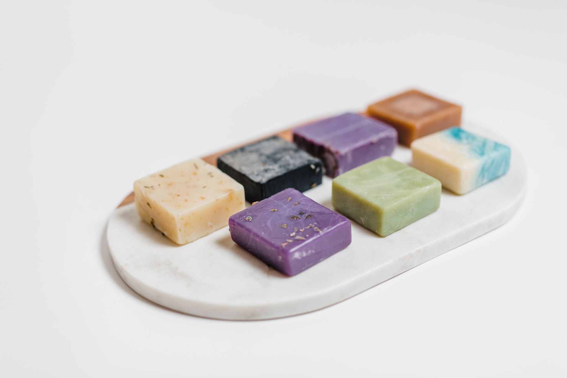 Colorful handmade soaps arranged on a marble serving tray.