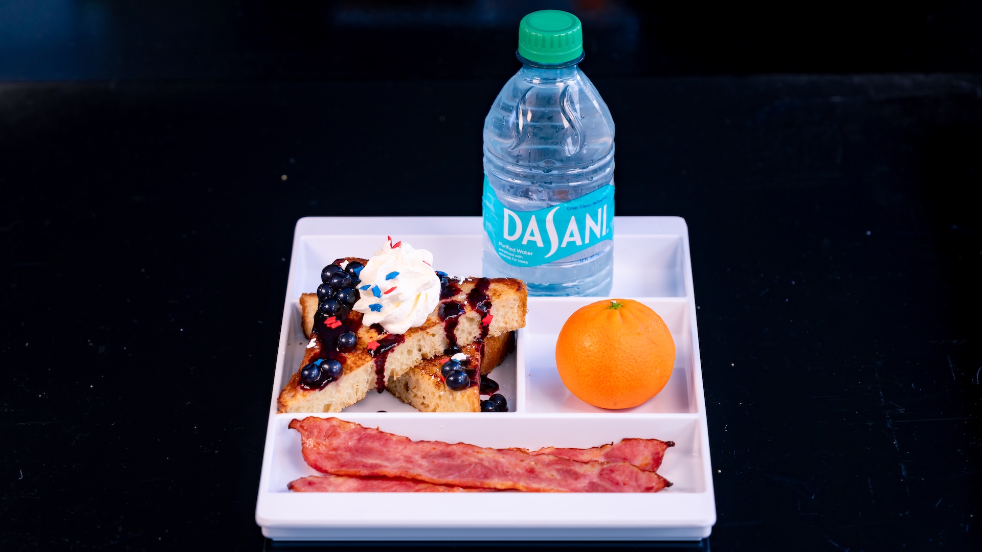 Disneyland Kids Meals Semi-Formulated French Toast with turkey bacon, blueberry-flavored popping spheres, berry Jamaica syrup, whipped cream, and sprinkles served with a Cuties Mandarin Orange and choice of small DASANI Water or small lowfat milk (only available during breakfast)