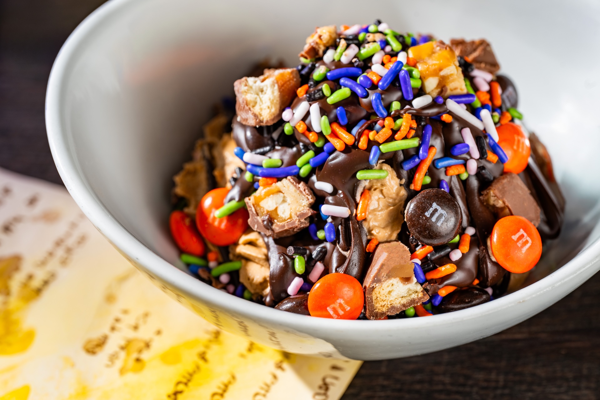 Candy Bowl Sundae: Vanilla soft-serve topped with chocolate cone dip, SNICKERS bar pieces, TWIX cookie bar pieces, and M&M&rsquo;S Milk Chocolate Candies Halloween Blend (Available during Mickey&rsquo;s Not-So-Scary Halloween Party only)