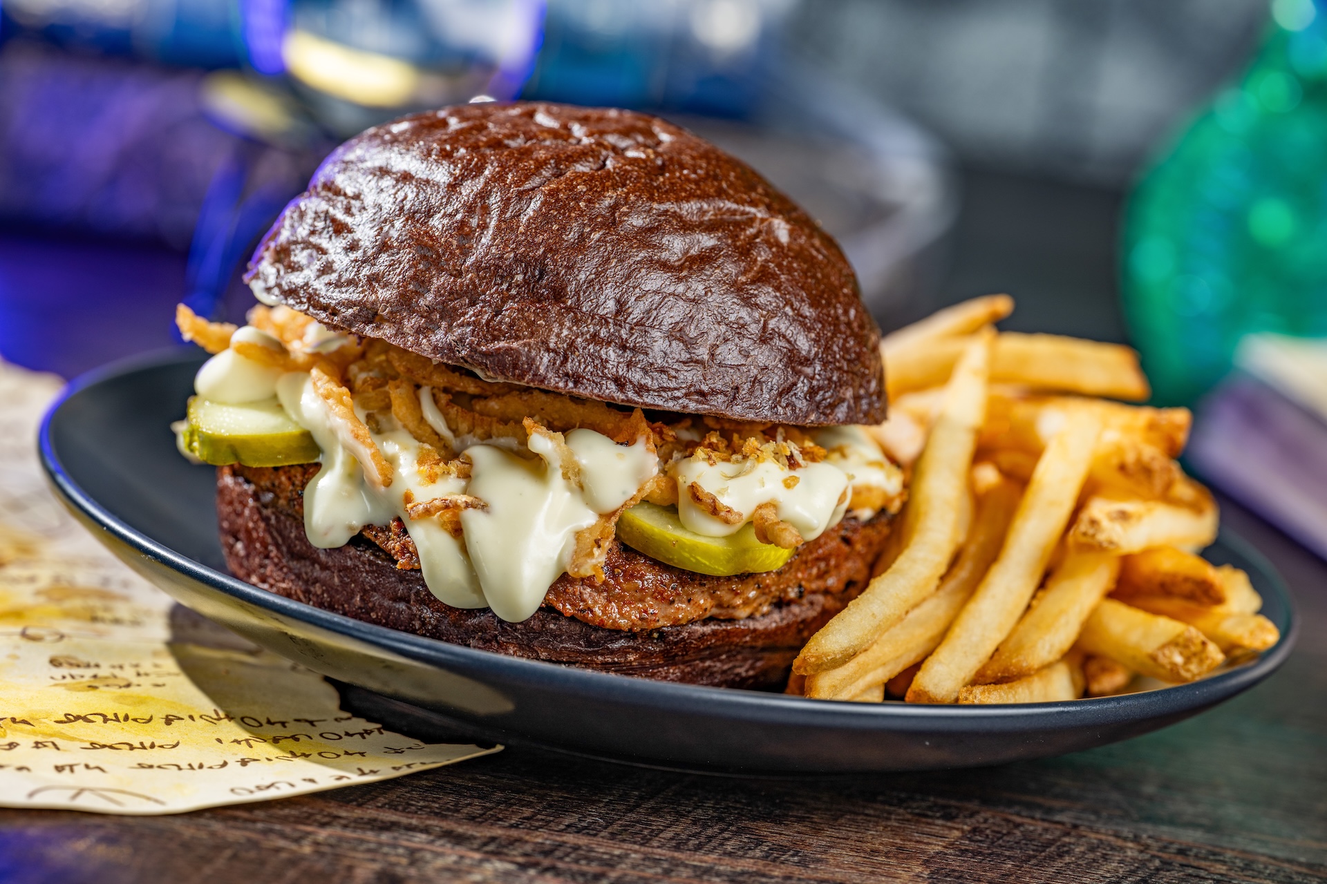 Fang-tastic Garlic Butter Burger: Angus beef with Boursin and brie fondue and garlic pickles on a toasted black bun. Served with french fries (New) (Available during Mickey&rsquo;s Not-So-Scary Halloween Party only)