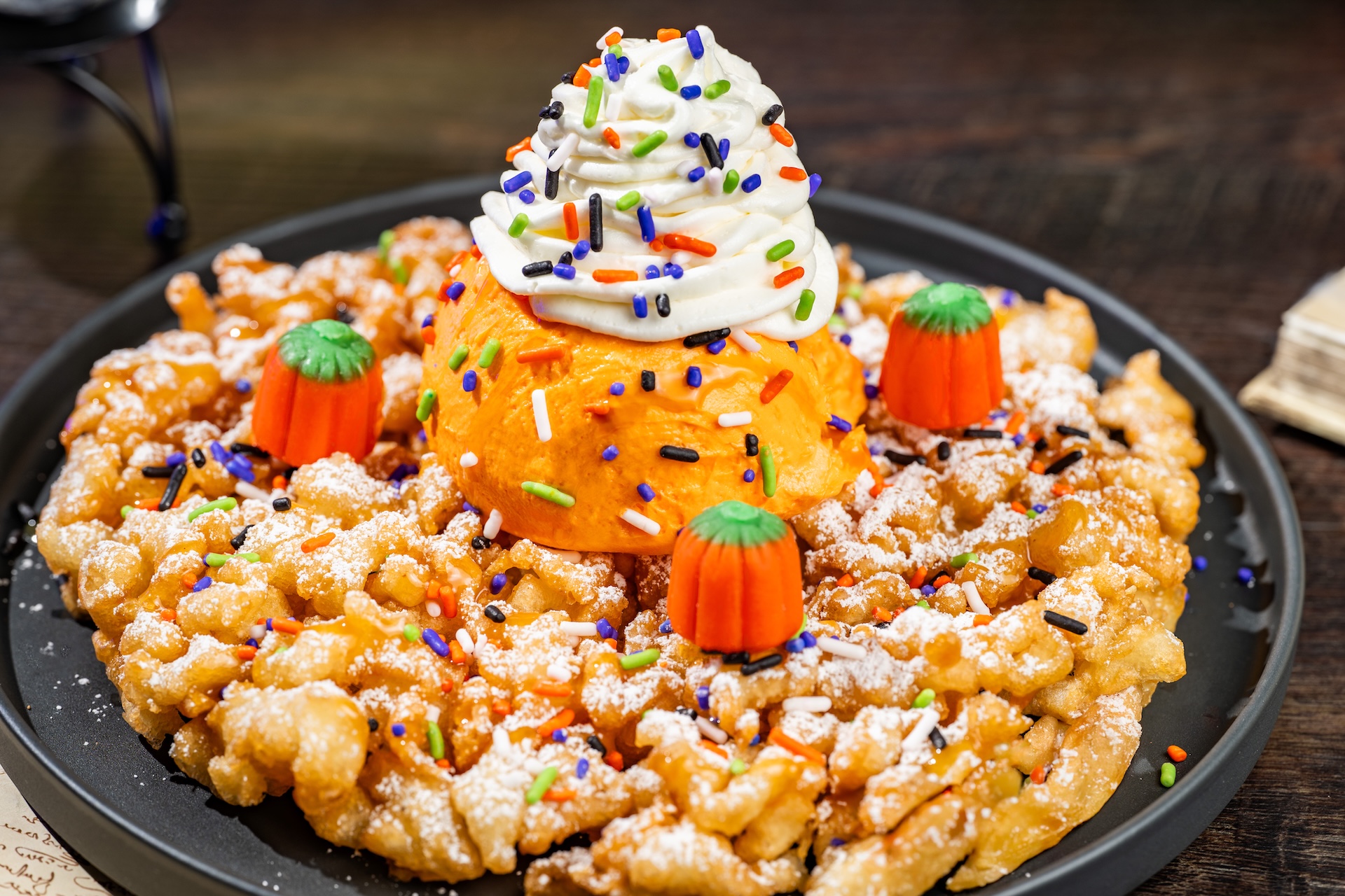 Pumpkin-spiced Funnel Cake Sundae: Pumpkin funnel cake topped with pumpkin gelato, whipped cream, pumpkin-spiced caramel, candy pumpkins, and sprinkles (Available during Mickey&rsquo;s Not-So-Scary Halloween Party only)