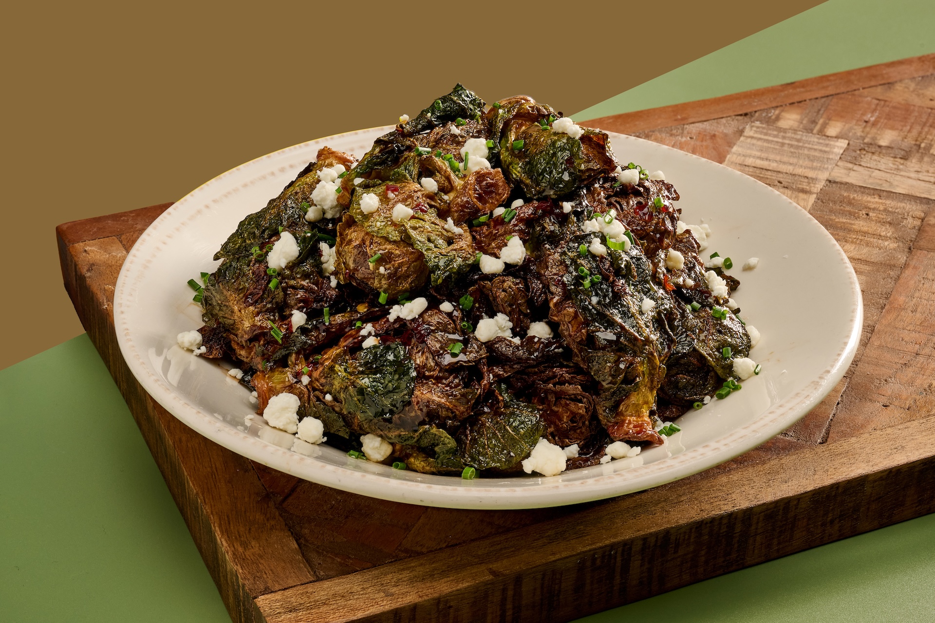 Fried Brussels Sprouts tossed in balsamic glaze drizzled with spicy honey and topped with crumbled goat cheese