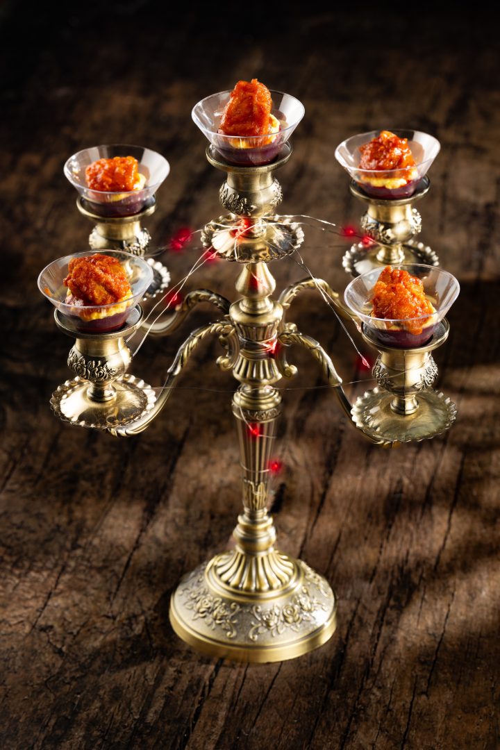 A decorative candelabra holding colorful Halloween-themed appetizers.