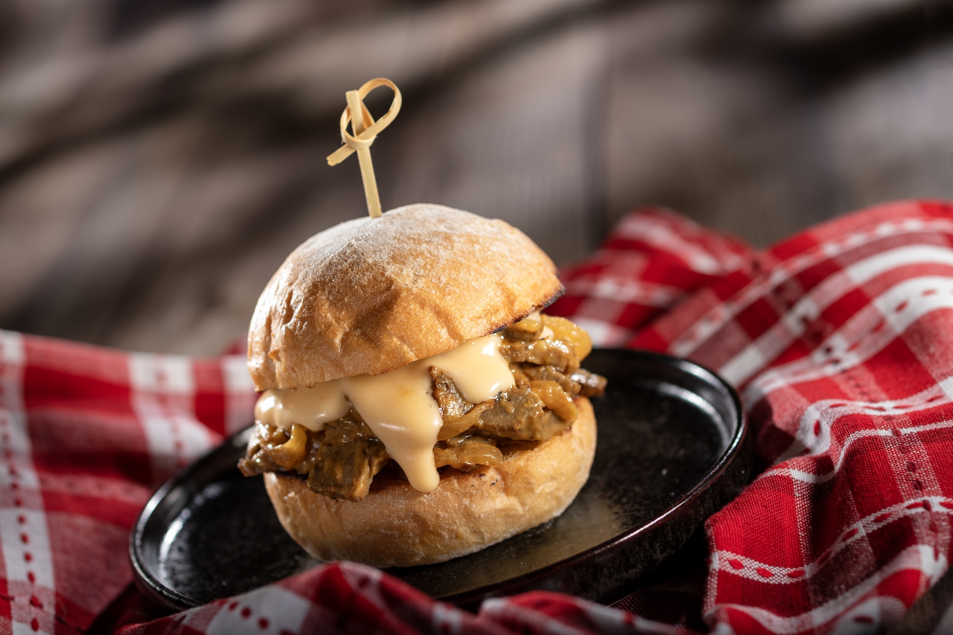 Smoked Brisket and Cheddar Melt: Chopped smoked brisket, caramelized onions, tangy barbecue, and cheddar sauce on a potato roll (New)