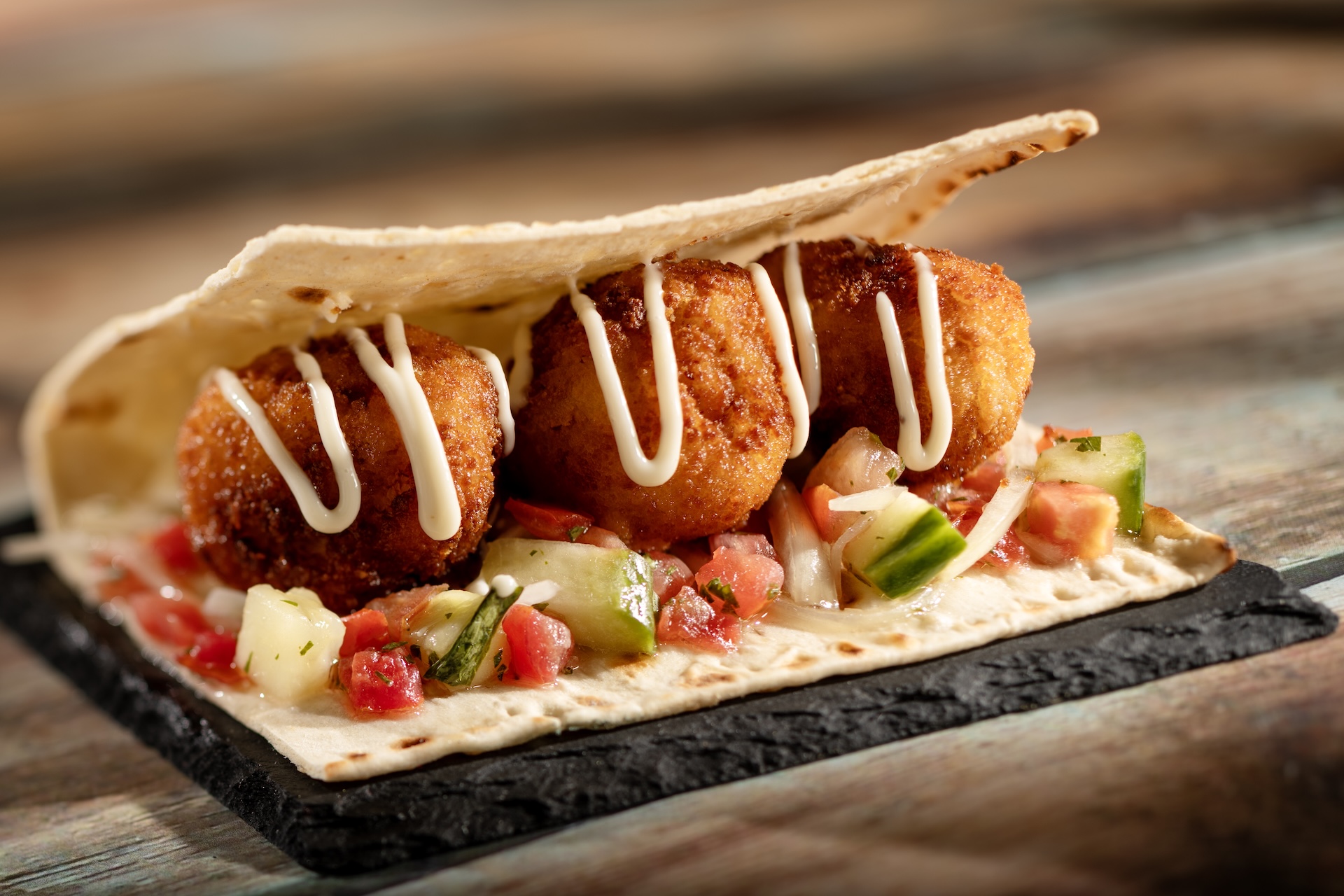 Plant-based Falafel Wrap with tomato-cucumber relish and garlic sauce served on warm Moroccan flatbread (Plant-based)