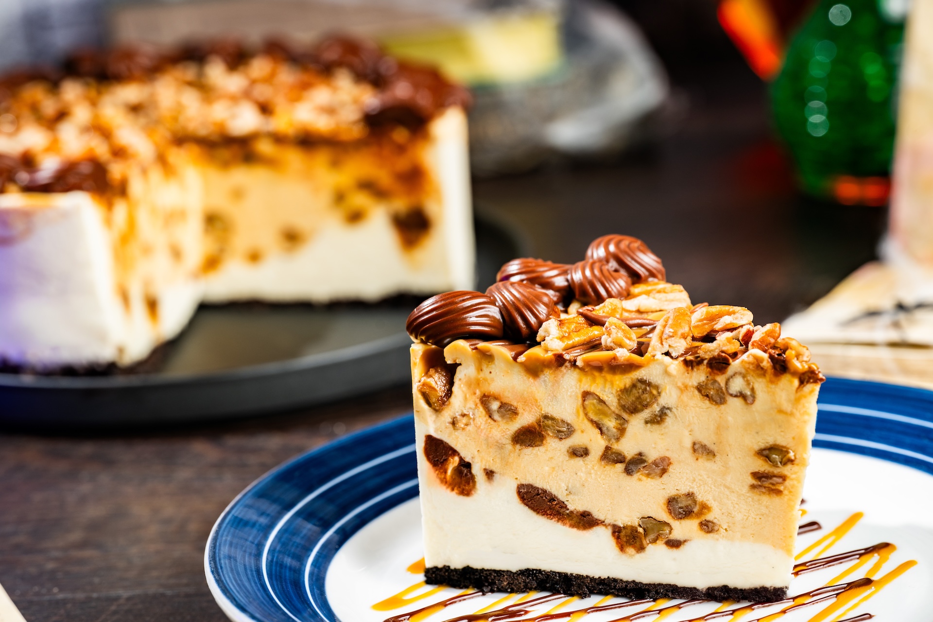 Phantom Pecan-Caramel Cheesecake: Layers of New York and caramel cheesecake with dulce de leche, chocolate ganache, and pecans on a chocolate crust (New)  