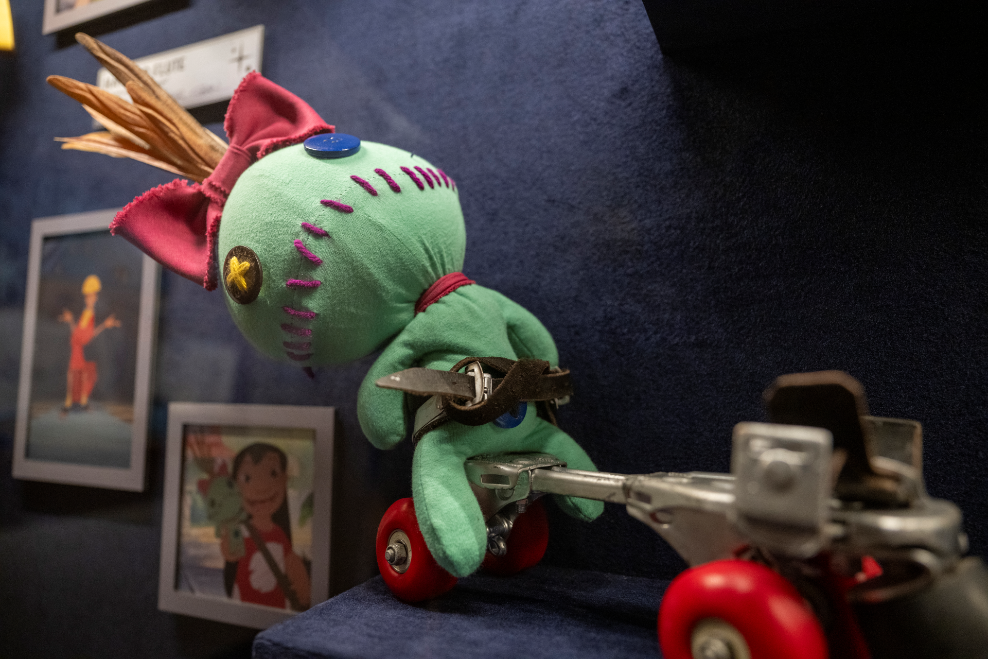 A green plush toy with a mohawk, sitting on roller skates.