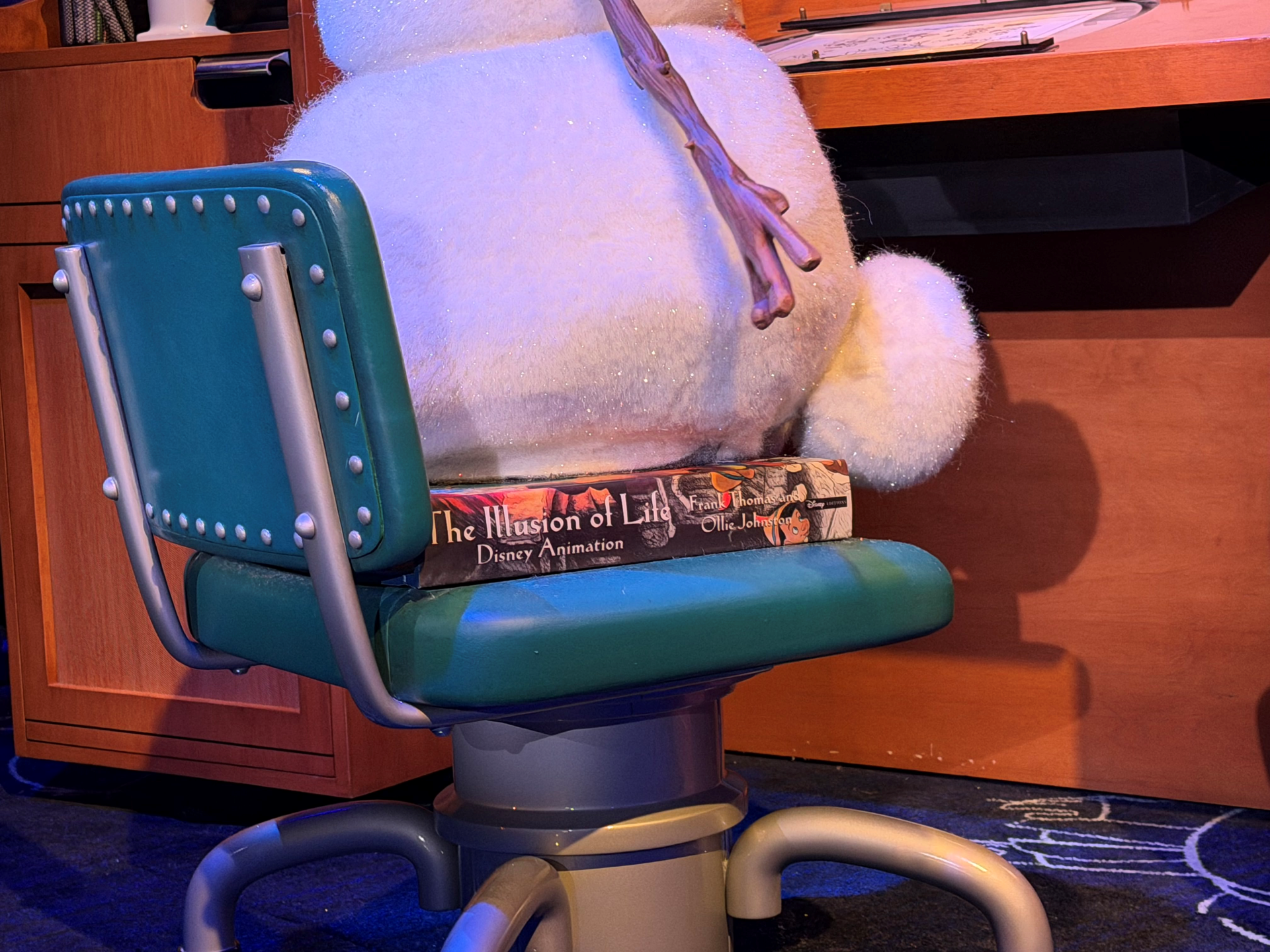 Olaf plush sitting on a green chair with animation books.