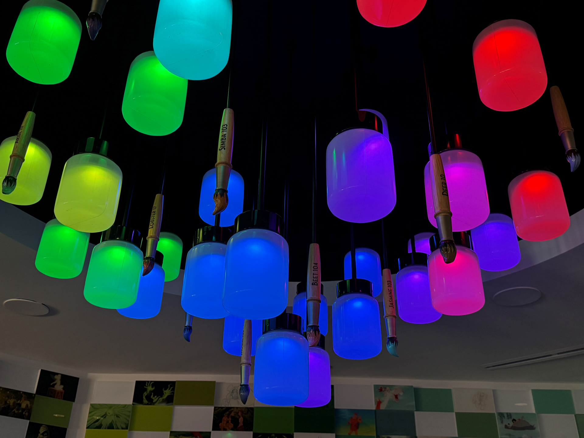 Colorful hanging lights shaped like paintbrushes in various hues.