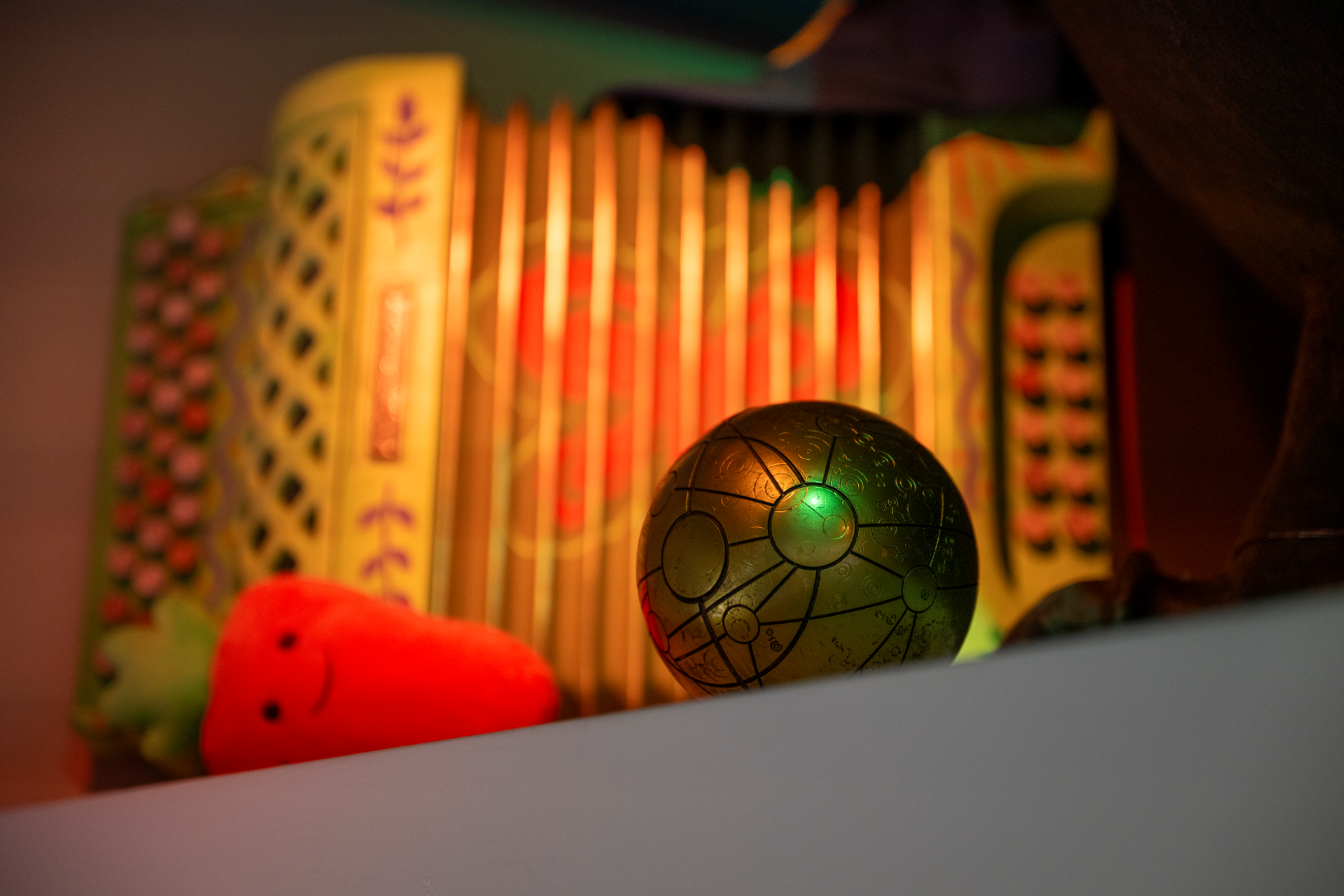 Colorful accordion and a green spherical object with a plush toy.