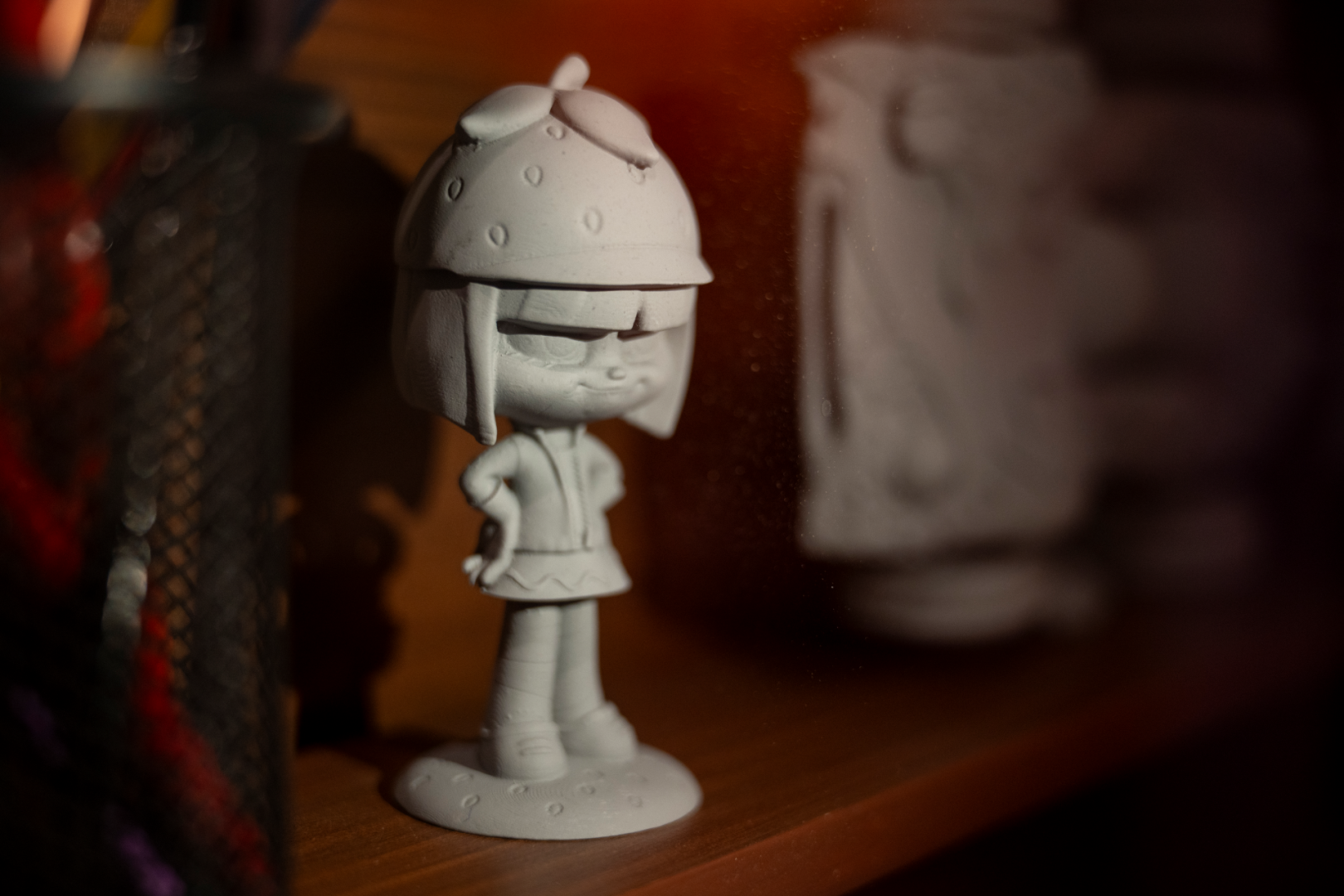 Gray figurine of a character with a strawberry hat, posed confidently.