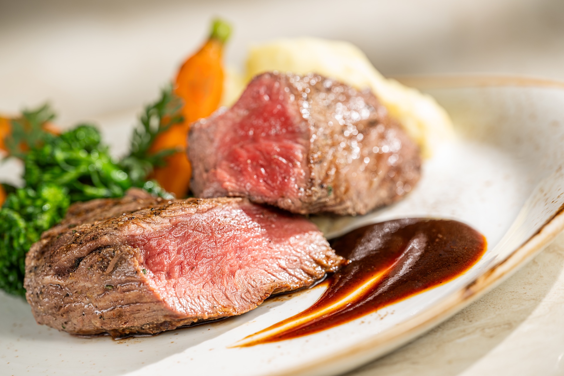 Char-grilled steak with sauce, garnished with vegetables and mashed potatoes.