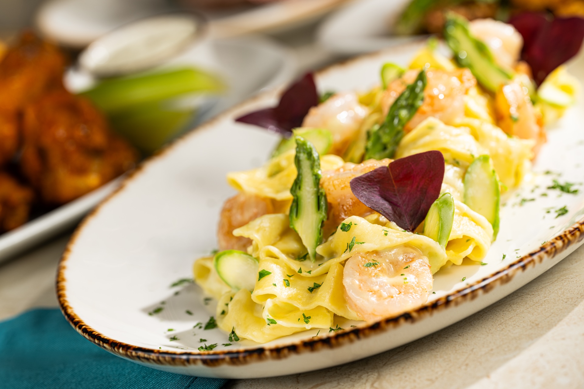 Pasta dish with shrimp, asparagus, and garnishes on a white plate.