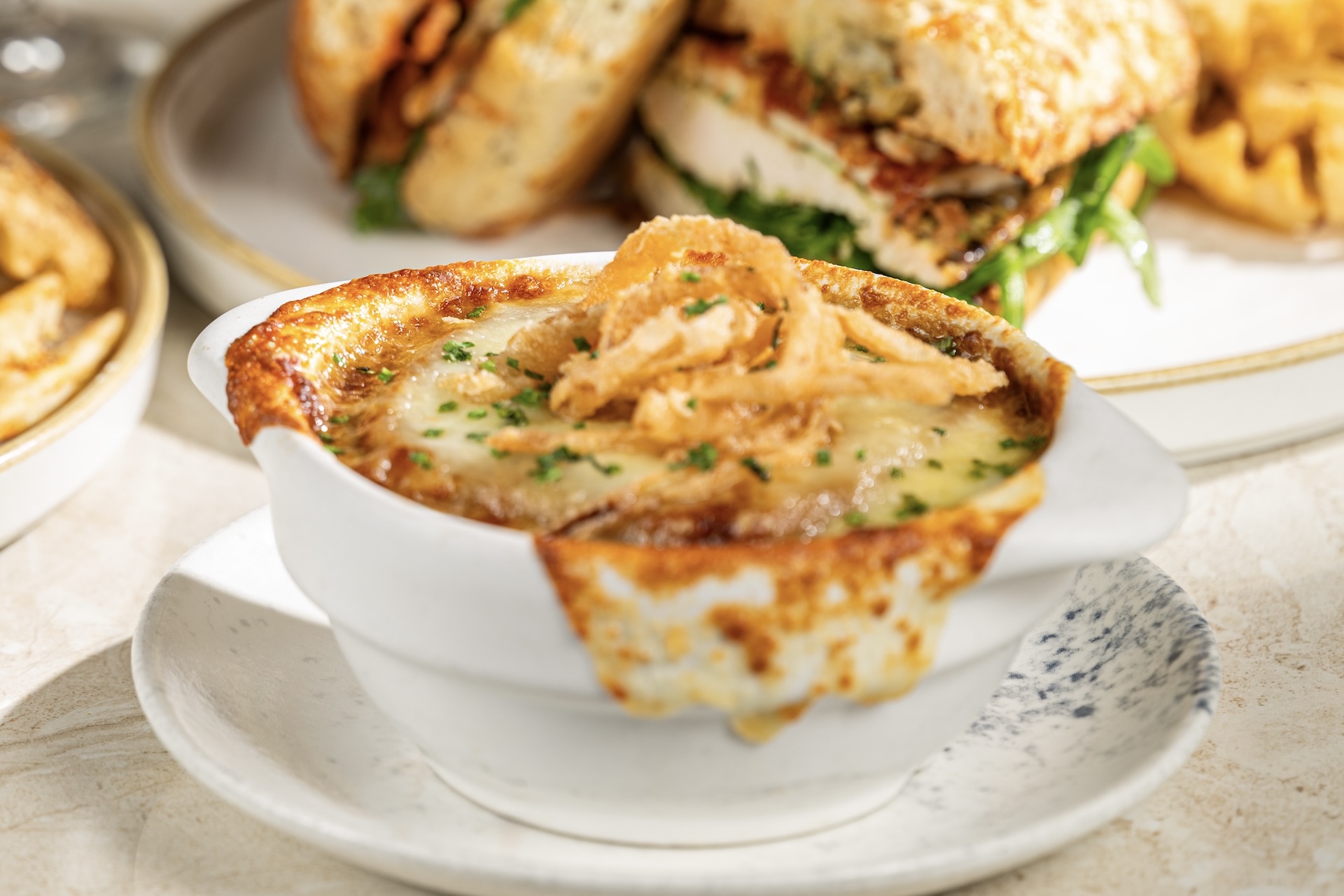 Onion soup topped with crispy onions, served in a white bowl.