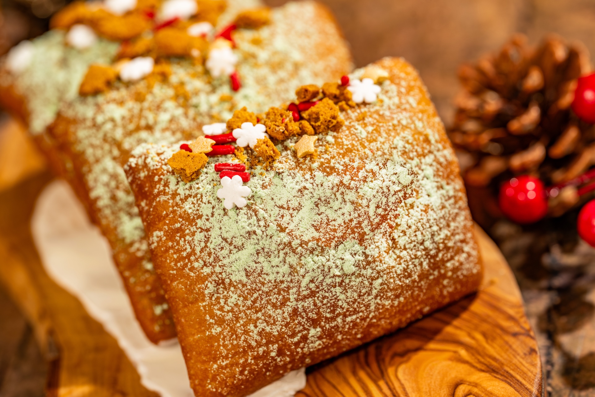 Gingerbread Cheesecake Beignets: Light and fluffy beignets dusted with powdered sugar and festive sprinkles over a gingerbread cheesecake icing (New) (Available during Mickey&rsquo;s Very Merry Christmas Party only) 