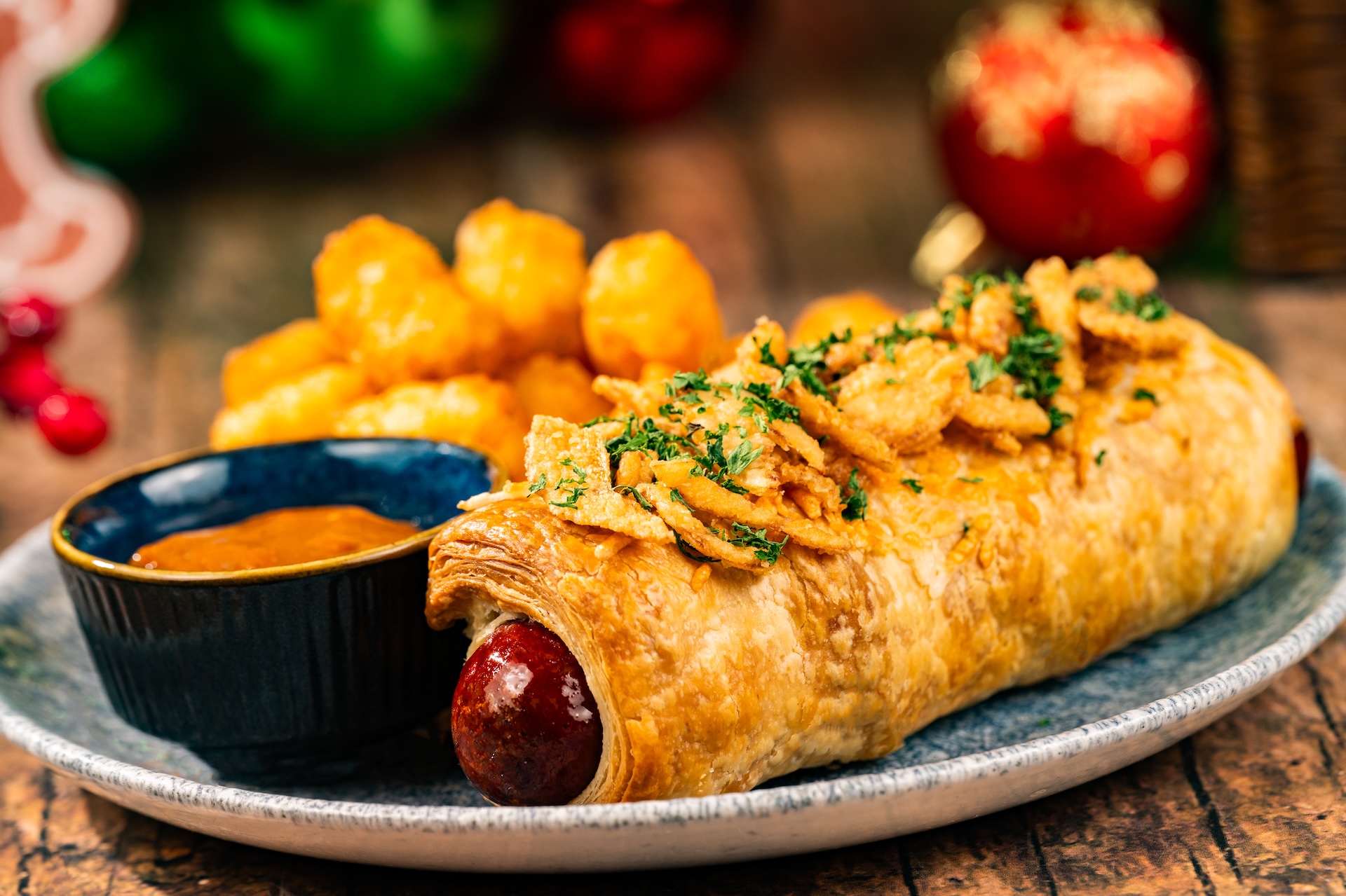 Pig in a Blanket: All-beef hot dog wrapped in Parmesan puff pastry, crispy onions, and honey mustard, and barbecue sauce served with tots (Available during Mickey&rsquo;s Very Merry Christmas Party only) 