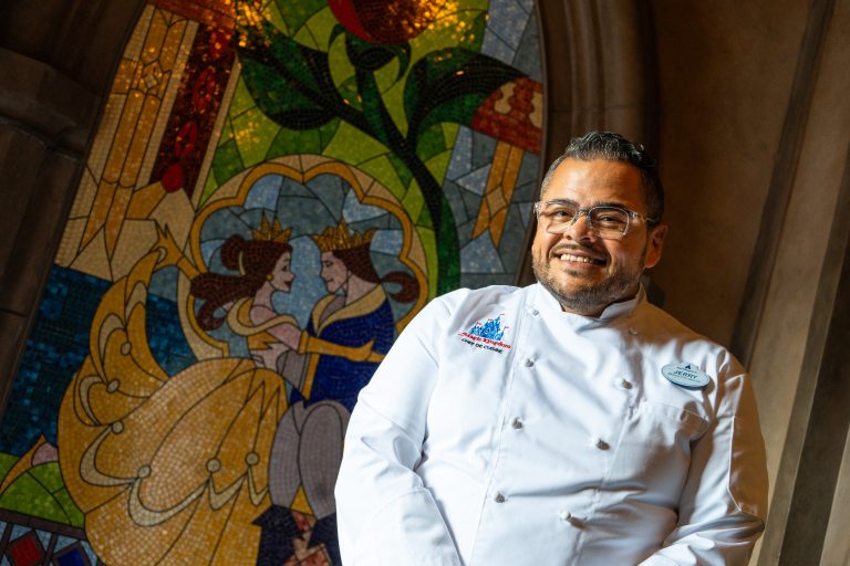 Chef Jerry smiling at the camera in front of Be Our Guest restaurant