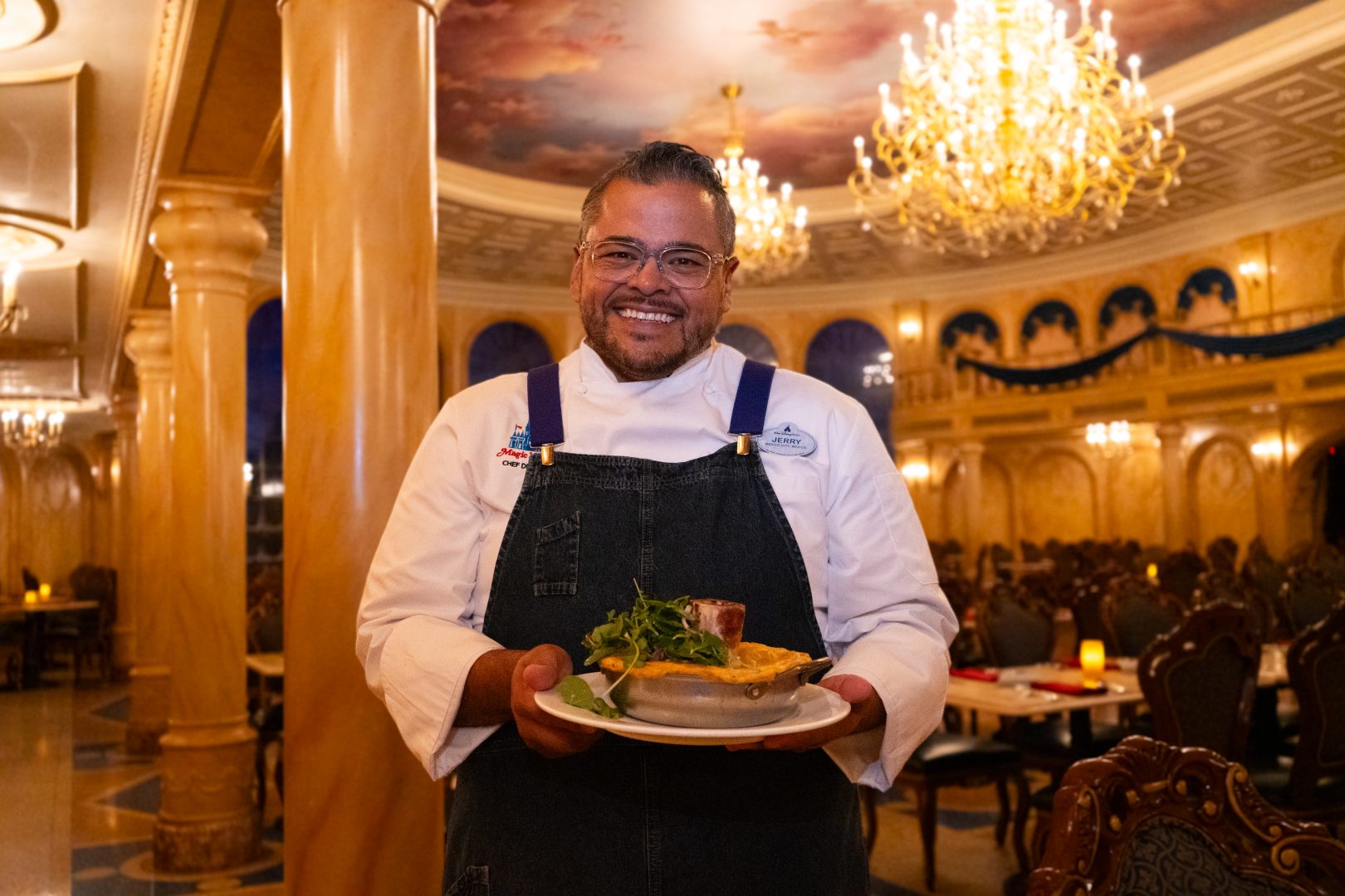 Chef Jerry smiling at the camera holing a dish.